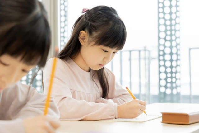 教室で鉛筆を持つ子供たち