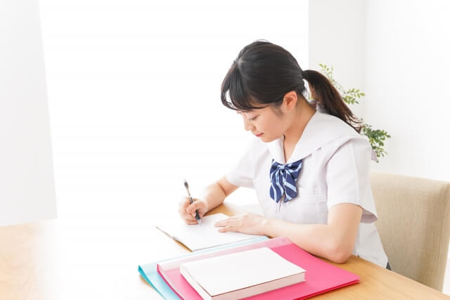 机でノートを取る女子学生の姿