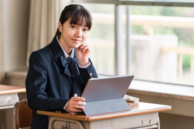 教室でタブレットを使う女子学生